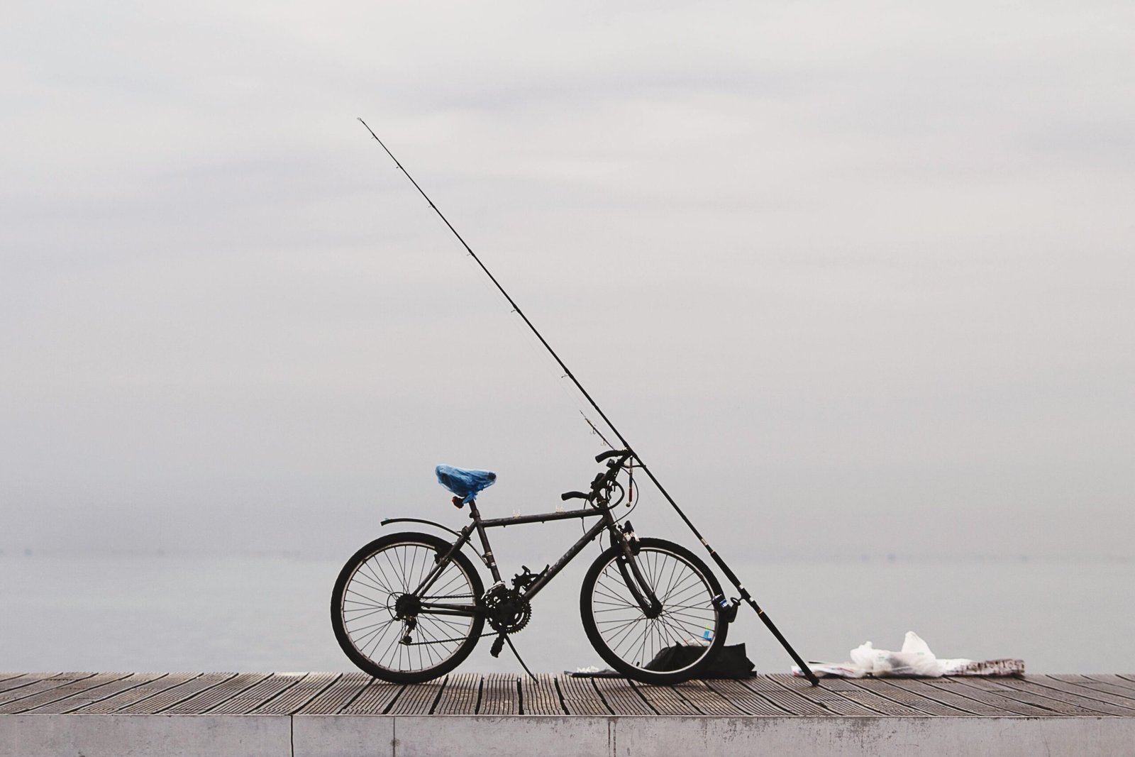 A vintage bicycle with fishing gear on a wooden pier overlooking the sea in Thessaloniki, Greece.